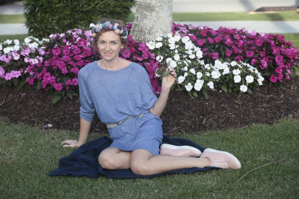 女人坐在花坛前的草地上。图片下载