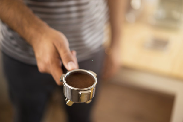 咖啡师拿着一个过滤机，里面装着现磨的咖啡图片下载