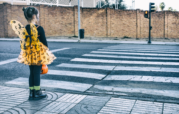 小女孩在斑马线穿着万圣节服装走向儿童聚会地点素材图片