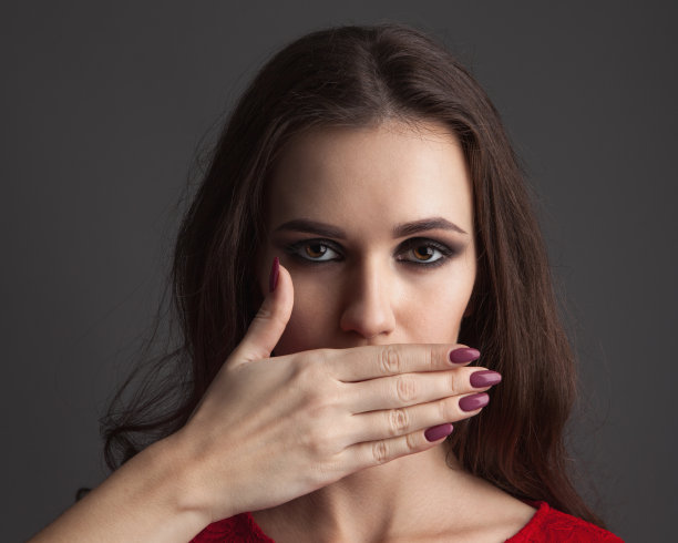 漂亮的年轻女子，双手捂着脸，遮住嘴。图片下载