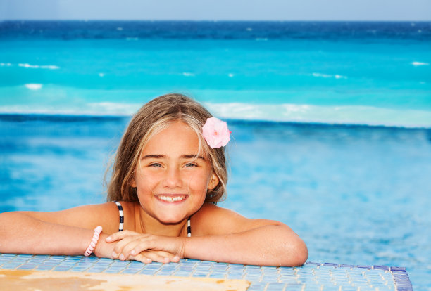 微笑的女孩在游泳池边上休息图片下载