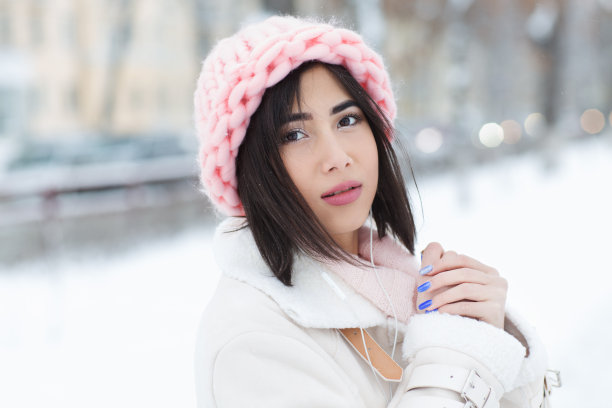 美丽的年轻女子穿着美丽诺羊毛柔和的颜色帽子早晨户外。冬季护肤、唇部护理、睫毛护理。美丽年轻的女人有乐趣在冬季公园。图片下载