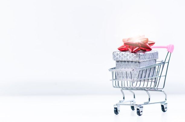 购物手推车与圣诞礼物。礼盒与红色丝带孤立的白色背景。圣诞装饰。图片下载