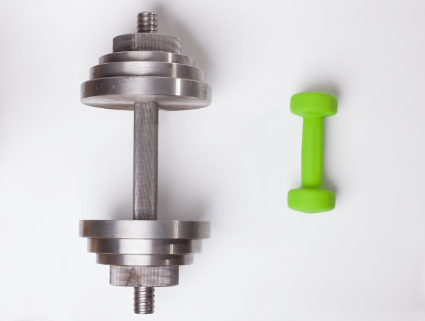 大而重的钢哑铃与小而绿的哑铃相比图片下载