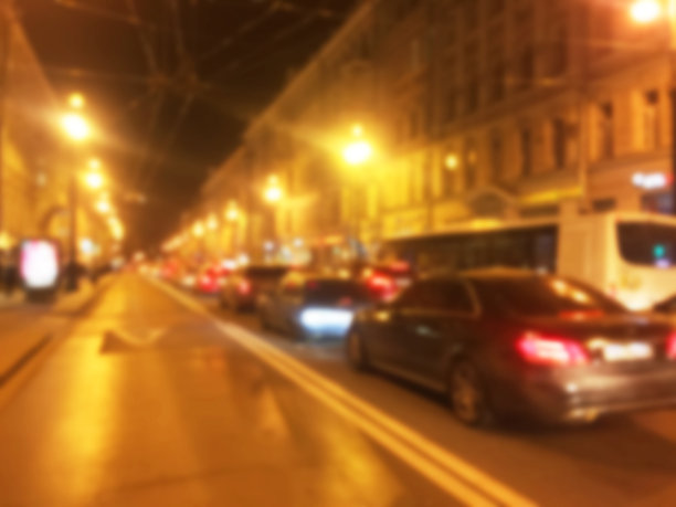 抽象模糊的背景在晚上。模糊的道路与散景街道的城镇和汽车。有空余停车位的停车场。城市街道上交通车辆的夜间灯光图片下载