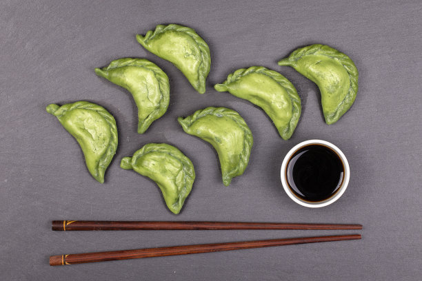 乌克兰和俄罗斯菜-绿色的vareniki或饺子与牛肉或土豆泥或软干酪在面团，连同螺旋藻在黑色的石板背景图片下载