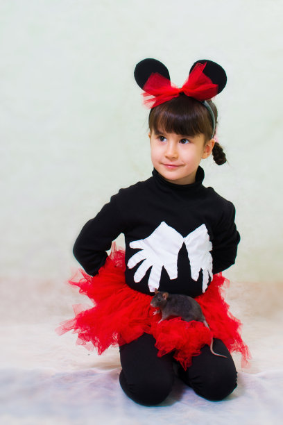 可爱的小女孩穿着熊的服装，有耳朵，拿着一只手鼠图片下载