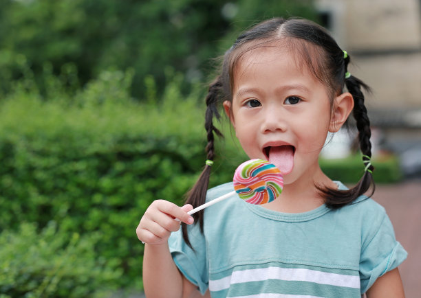 拿着棒棒糖的可爱快乐亚洲小女孩素材图片