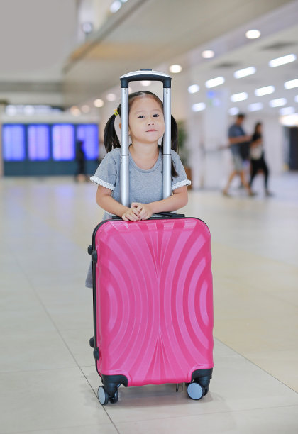 在机场带着行李箱的可爱小女孩。图片下载