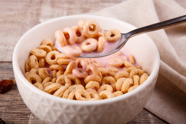 早餐，玉米圈与酸奶，葡萄干在一个木制的背景，特写照片图片下载