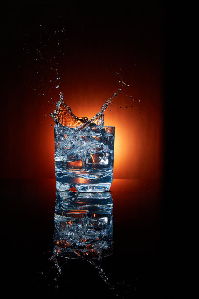 将冰块和水倒入一个透明的玻璃杯中。图片下载