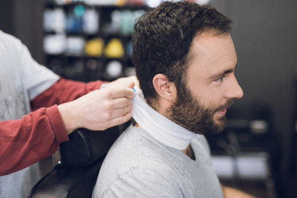 一个人坐在一个男人理发的理发店里的椅子上。图片下载