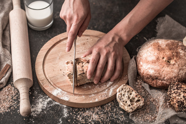手里拿着新鲜的面包，老木头背景的特写图片下载