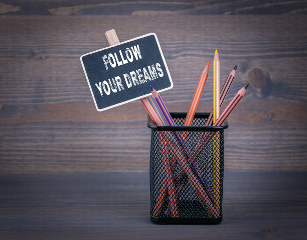 追逐你的梦想。一个小黑板，粉笔和彩色铅笔在木头背景上图片下载