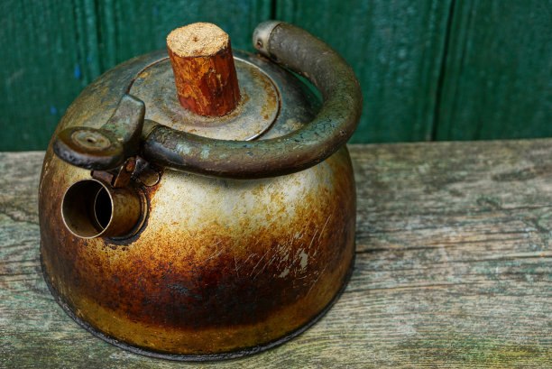 一个又旧又脏的金属茶壶放在木板上图片下载