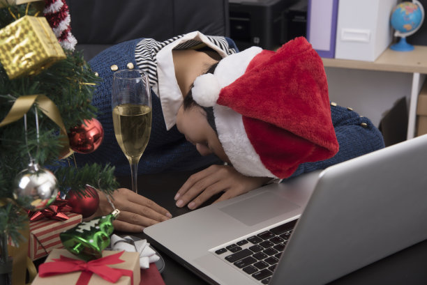 在办公室庆祝完圣诞节后，女人们戴着圣诞老人睡在她的办公桌上。图片下载