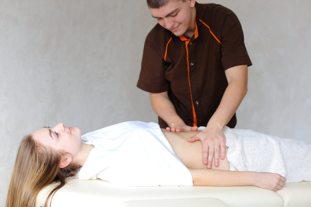 强壮的男性按摩师用轻柔的手动作揉c腹部图片下载