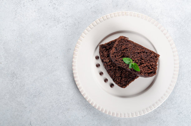 两片带薄荷叶的巧克力蛋糕放在白面包上图片下载