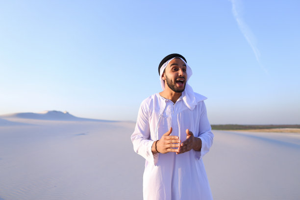 在沙漠顶端微笑行走的快乐穆斯林男人图片下载