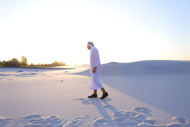 自信的阿拉伯男子在白色沙漠中行走图片下载
