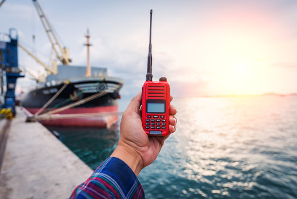 微笑的码头工人拿着无线电和船舶背景图片下载