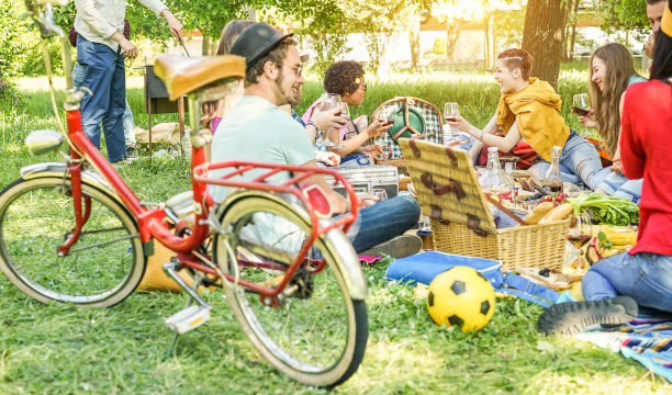 快乐的朋友在城市公园户外野餐-年轻时尚的人们一起喝酒和吃饭-聚焦顶级中心女孩和男人烹饪烧烤-青春，食物和友谊的概念素材图片