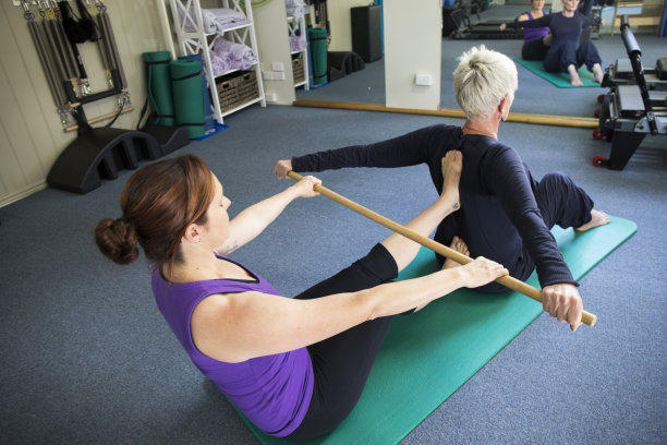 瑜伽课上的女人用棍子做伸展运动图片下载