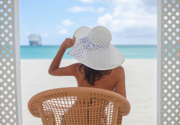 后视图美丽的年轻女子坐在热带海滩上看着水平图片下载