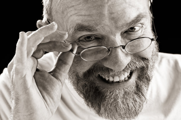 满脸胡须的男人微笑着从眼镜上方偷窥图片下载