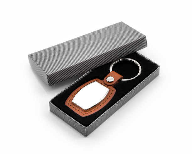 白色背景上的皮革钥匙圈。时尚钥匙链在包装盒。纪念品或配件。图片下载