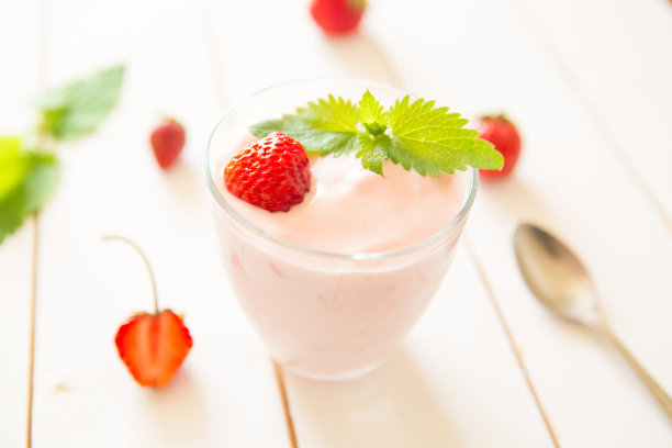 白色木桌上放着新鲜的自制酸奶和草莓。健康的食物图片下载