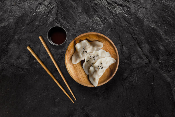 一盘亚洲饺子，配黑色石板上的酱油素材图片