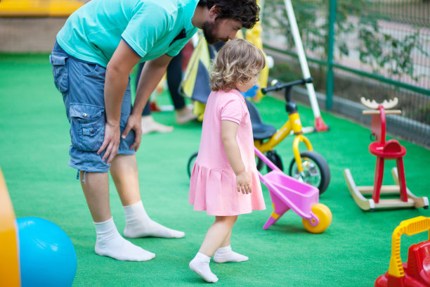 小女孩和她爸爸在操场上玩。图片下载