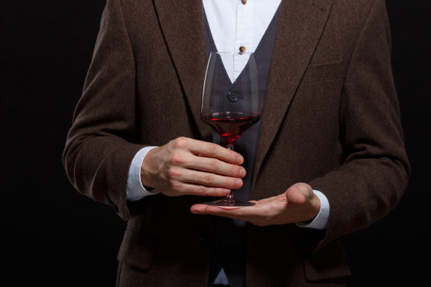 时尚的男人拿着一杯酒的手掌在一个黑色的背景图片下载