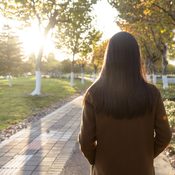 一幅年轻女子靠树站在公园里的肖像图片下载