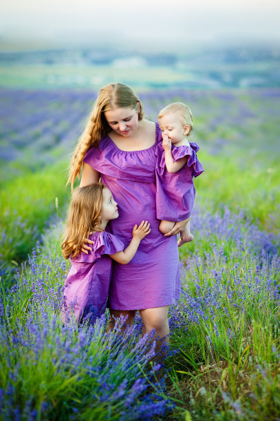 年轻的母亲拥抱两个孩子的照片，幸福的家庭的特写，可爱的深色头发的女性和两个女儿在春天的户外，微笑的脸，幸福和爱的概念图片下载