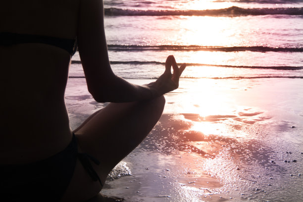 年轻女子的剪影在日落海滩沉思。图片下载