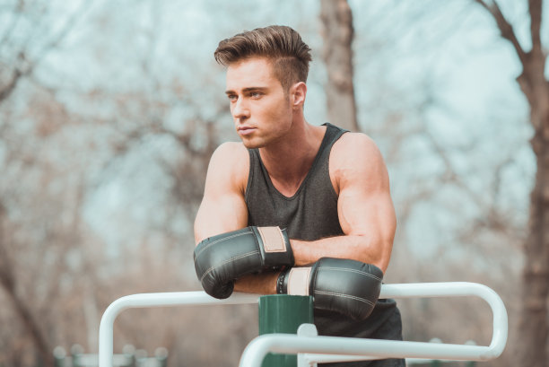 戴拳击手套的男人靠在锻炼杆上图片下载