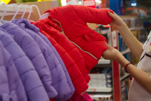 购物的年轻女子，手工查看架婴儿夹克在商店图片下载
