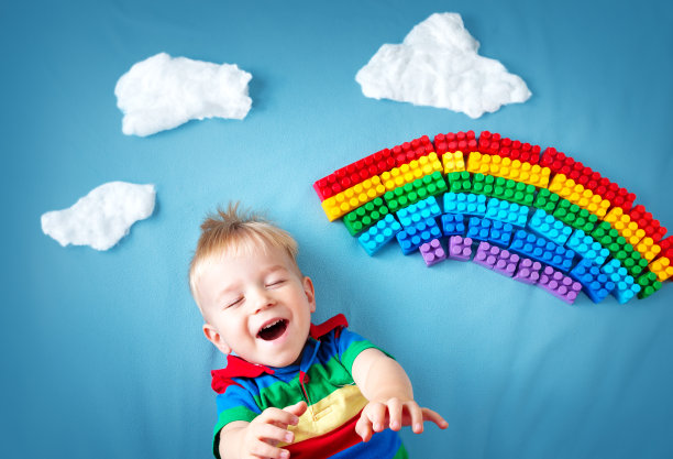 小男孩躺在有彩虹和云彩的毯子上图片下载