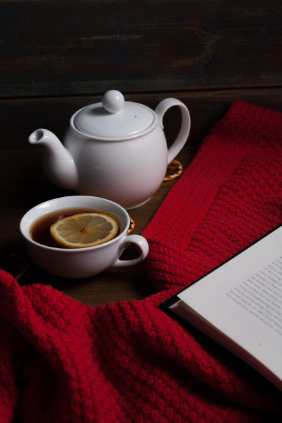 温暖的红色针织格子，热茶和书的茶杯和茶壶图片下载