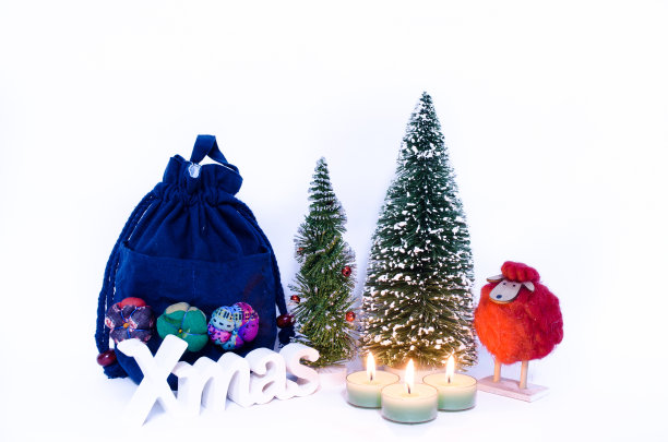 三支蜡烛，两棵圣诞树，一个礼物袋和一只红羊图片下载