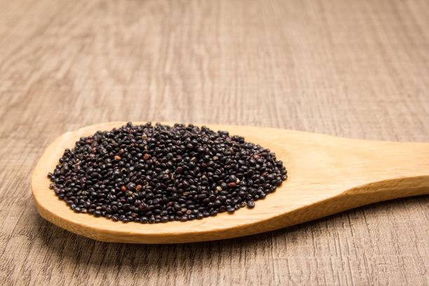 黑色奎奴亚藜种子。木勺里的谷物。乡村。图片下载