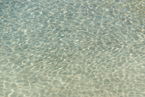 光在带有小波浪的清澈水中的折射。背景图片下载