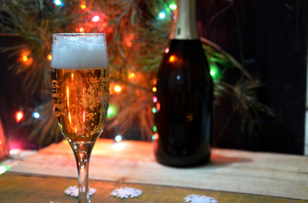 以香槟为背景的两杯香槟。挂着圣诞彩灯的圣诞树。新年和圣诞节图片下载