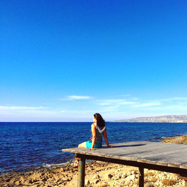 女人坐在海边的木甲板上看着大海图片下载