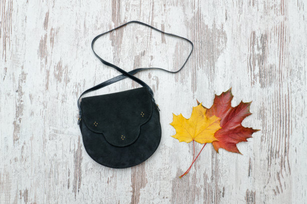 黑色手袋上的木制背景和枫叶。时尚的概念。图片下载