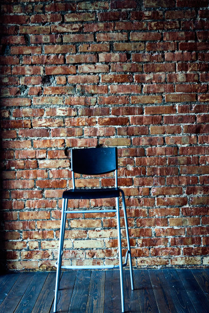 砖墙背景上的黑色现代椅子。图片下载