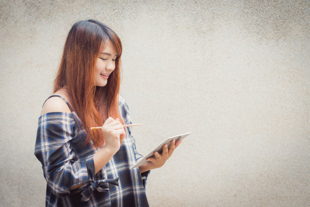 微笑年轻美丽的亚洲女人思考与写书在混凝土墙的背景。复古效果风格的图片。图片下载