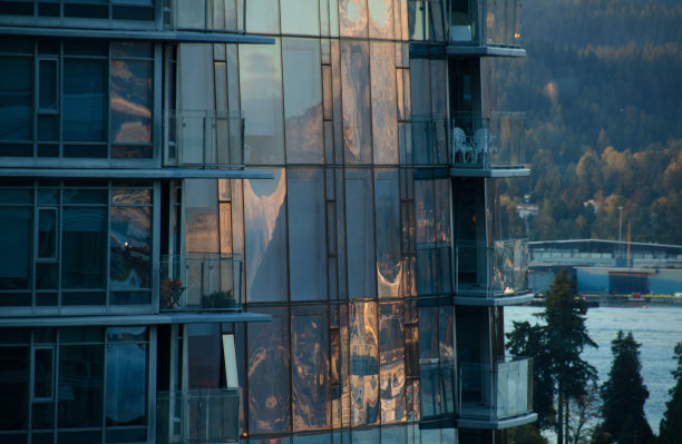 西摩山日落的倒影在摩天大楼的窗户附近的煤港，不列颠哥伦比亚省图片下载